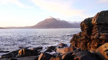 Denizde gün batımına dakika. Isle of Skye İskoçya'da taştan keskin çökmesini dalgalar. Köpüklü deniz seviyesi. Büyük siyah taşlar ve keskin rock Hebrides köpüklü Denizi üzerinde yuvarlanır. Turist resort. 