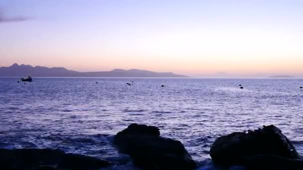 Abend in der Bucht von Elgol an der Westküste der Insel Skye in Schottland bei einem windigen Sonnenuntergang. schneebedeckte Berge auf der Soay-Insel über dem Meer der Hebriden, Wellen, die auf Felsbrocken und scharfen Felsen krachen — Stockvideo