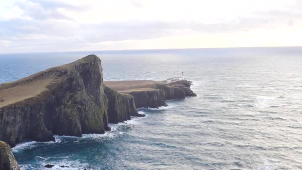Hermoso Neist Point, delgada escupida de tierra con famoso faro al final. Costa oeste de la Isla de Skye en Escocia dentro de la dura puesta de sol ventoso. Faro luminoso sobre el mar de las Hébridas . — Vídeo de stock