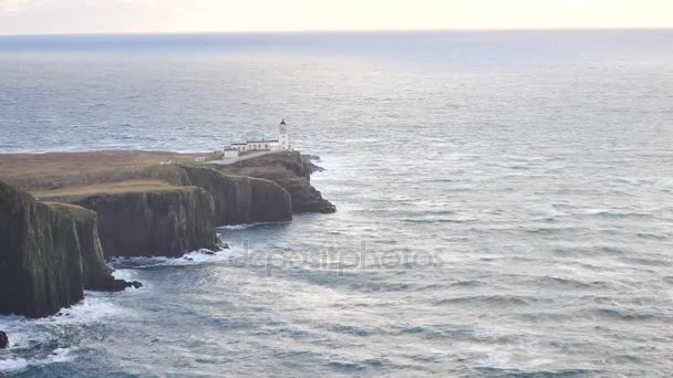 Hermoso Neist Point, delgada escupida de tierra con famoso faro al final. Costa oeste de la Isla de Skye en Escocia dentro de la dura puesta de sol ventoso. Faro luminoso sobre el mar de las Hébridas . — Vídeo de stock