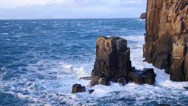 Grandes ondas fortes batendo contra a rocha afiada da Ilha de Skye, na Escócia. Nível do mar espumoso. Pedras pretas grandes arredondadas e torre rochosa aguda acima do mar espumoso das Hébridas. Resort turístico . — Vídeo de Stock
