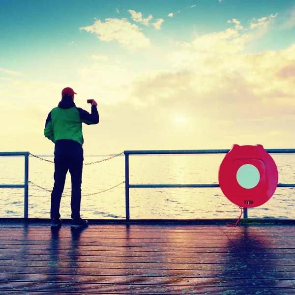 Man stand at handrail on mole and looking over sea to morning horizon