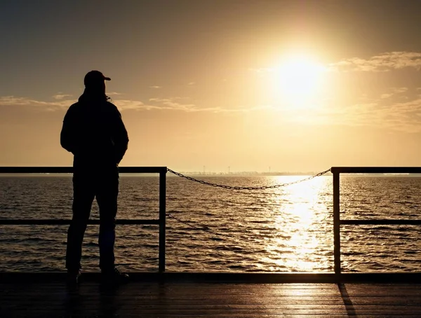 Homme grand adulte à bord du quai regarder au-dessus de la mer au soleil du matin. Niveau d'eau lisse — Photo