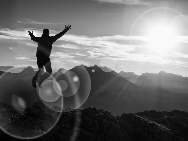 Lens flare effekt. Båge ljus cirklar. Crazy hiker hoppning på toppen av berget. — Stockfoto