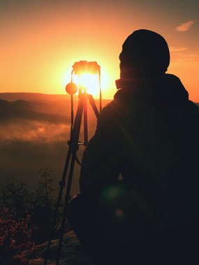 Amatör fotoğrafçı kaya tepe üzerinde ayna kamera ile fotoğraf çeker. Rüya gibi adamlara manzara, Bahar Turuncu pembe puslu sunrise bir güzel vadi