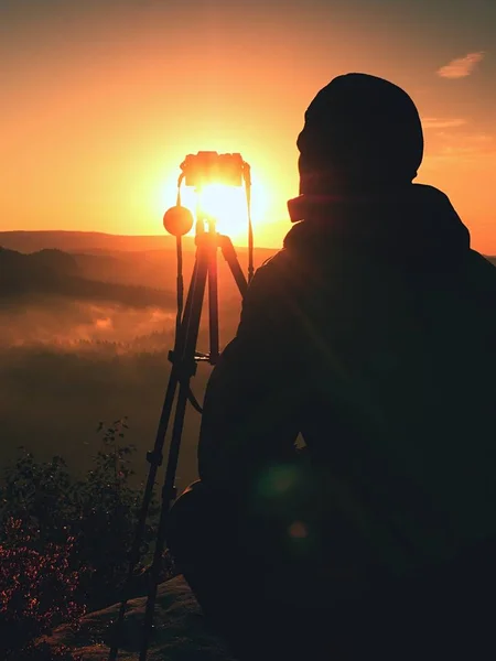 Photographe amateur prend des photos avec un appareil photo miroir au sommet du rocher. Paysage brouillard rêveur, printemps orange rose lever de soleil brumeux dans une belle vallée en contrebas — Photo