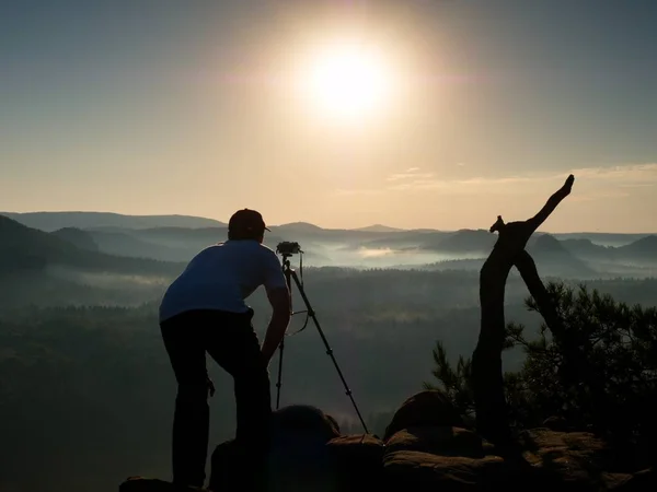 Fotógrafo tira fotos com câmera no pico do rock — Fotografia de Stock