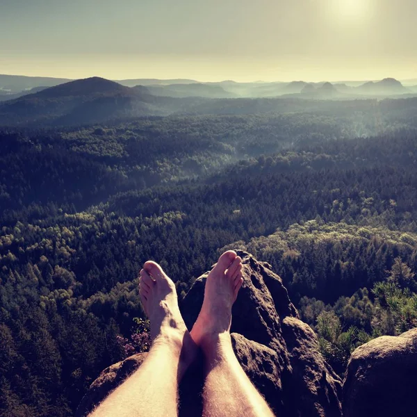 Naked male legs take rest on peak. Outdoor activities