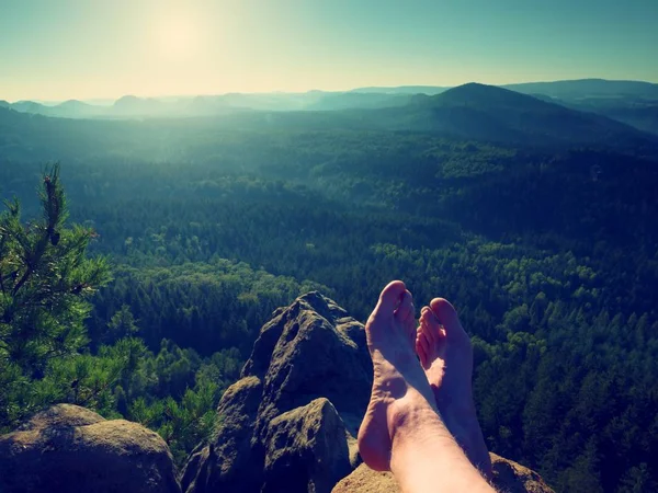 Naked male legs take rest on peak. Outdoor activities