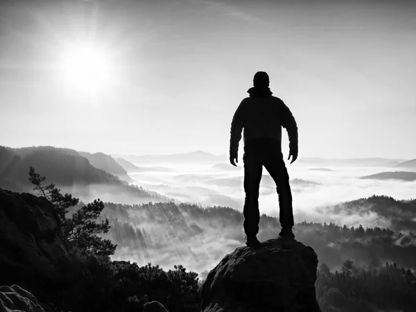 Männersilhouette, die hoch auf Klippen klettert. Wanderer erklimmt Gipfel und genießt Aussicht. — Stockfoto