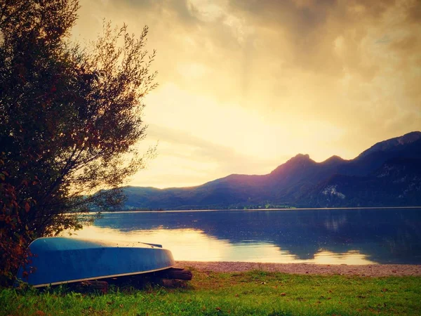 Upside down fishing paddle boat on bank of Alps lake. Smooth levelof autumnal lake. — Stock Photo, Image