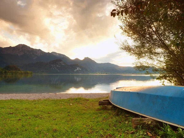 Upside down fishing paddle boat on bank of Alps lake. Smooth levelof autumnal lake. — Stock Photo, Image