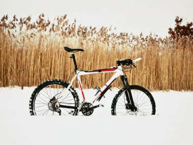 The  mountain bike stay in snow. Snow melting on dark off road tyre. clipart