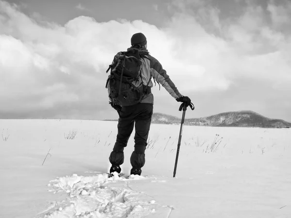 Tramp s batohem na sněžnicích v hluboké návěje. Muž s chůze do kopce. — Stock fotografie