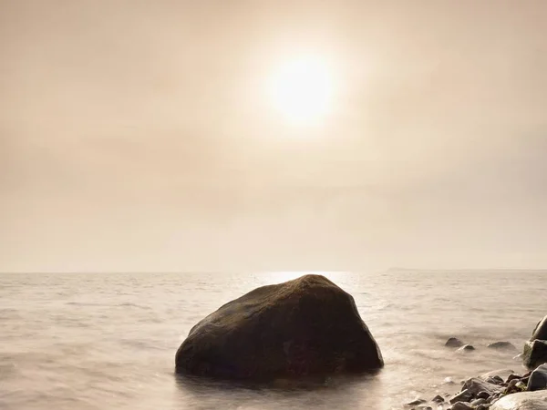 Balvany na pobřeží ostrova zastat z hladké moře. Kamenité pobřeží vzdoruje vlnám — Stock fotografie
