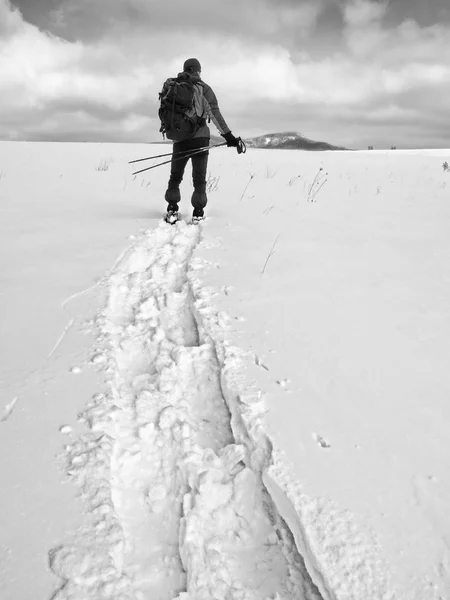 Caminante con mochila raquetas de nieve en deriva profunda. Hombre con paseo en la colina . —  Fotos de Stock