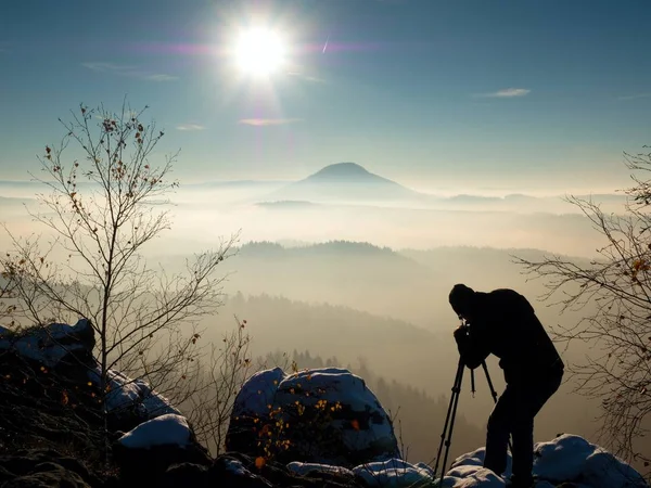 Fotógrafo toma foto de rocas heladas cubiertas con nieve fresca en polvo . — Foto de Stock