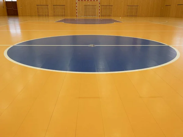 Баскетбольная площадка внутри. Белые линии и синяя площадка в холле. Ганбольные ворота у стены. Окрашенный деревянный пол спортивного зала с красочными линиями разметки. Спортивный зал школы — стоковое фото