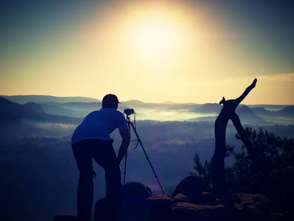 Fotógrafo no pico do rock. Queda paisagem nebulosa — Fotografia de Stock