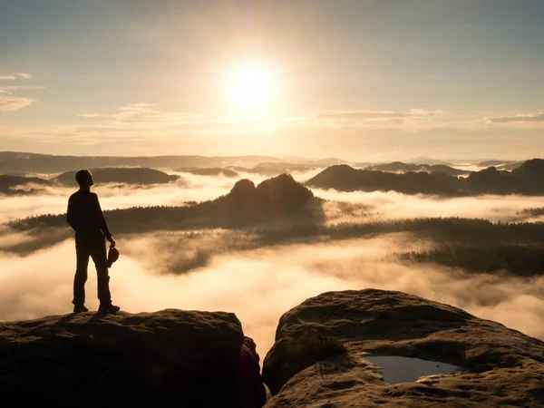 Силуэт туриста, стоящий на скалистой вершине над туманной долиной . — стоковое фото