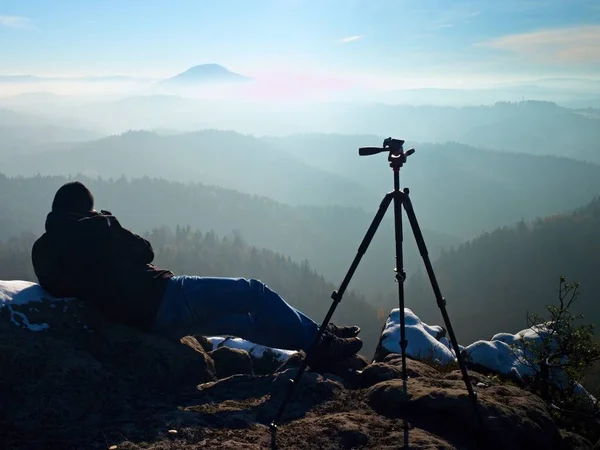 Man takes photos with camera on sharp rock. Dreamy fogy landscape — Stock Photo, Image