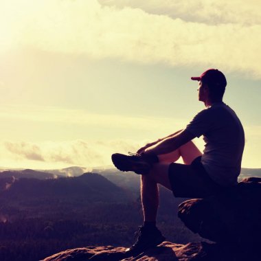 Adam turist maruz kayanın üzerinde oturmak. Nokta keskin rock ile görüntüleyin. Adam kaya tepe üzerinde oturmak. Renkli sis ve orman Vadisi'nde sis içine izlerken gözler yükseltilmiş kollu gölgeleme uzun yürüyüşe çıkan kimse.