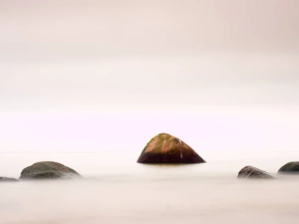 Romantic sea. Boulder stick out from smooth wavy sea. — Stock Photo, Image