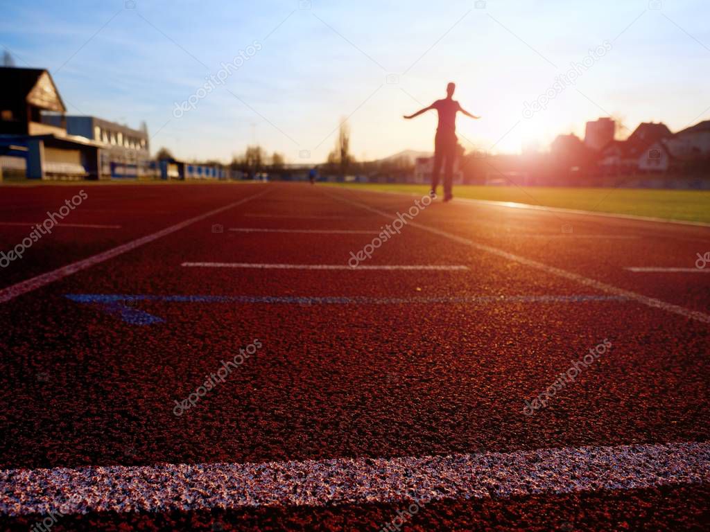 Sportsman on running stadium racetrack. Adult in evening training