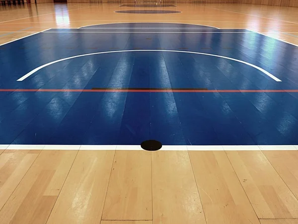 Campo de basquetebol lá dentro. Linhas brancas e playfield azul no corredor. Portão de Hanball na parede. Piso de madeira pintado de salão de esportes com linhas de marcação coloridas. Salão de ginástica escolar — Fotografia de Stock