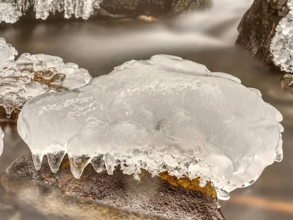 Kristalleis mit Rissen im Inneren. Herabgefallene Eiszapfen unter Wasserfall, steinigen und chaotischen Bachufer. Extreme Einfrierung — Stockfoto