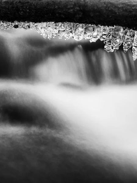 Eisglatte Äste über dem kalten Bach. Spiegelungen in Eiszapfen — Stockfoto