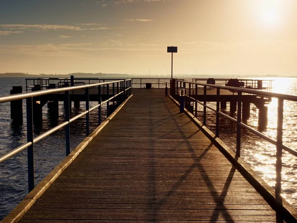 Långa träbrygga vid kusten, kall morgon, lugn tyst dag — Stockfoto