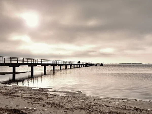 Långa träbrygga vid kusten, kall morgon, lugn tyst dag — Stockfoto