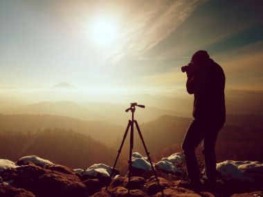 Karlı cliff üzerinde profesyonel doğa fotoğrafçısı. 