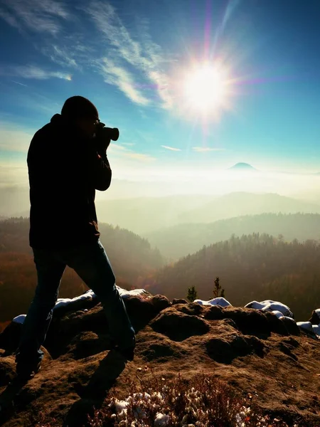 Der große Mann fotografiert mit der Spiegelkamera am Hals. schneebedeckte Felsen — Stockfoto