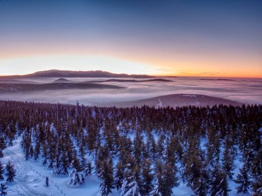 Pembe turuncu güneşin doğuşunu yukarıda puslu kış dağlar