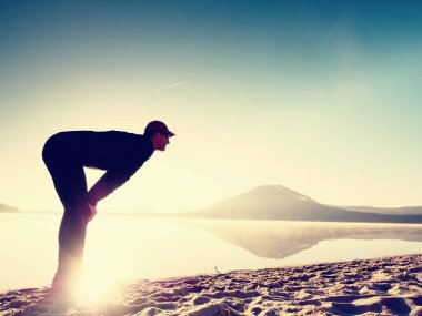 Kumsalda egzersiz adam. Egzersiz ve gölde germe etkin adam silüeti