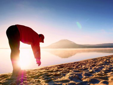 Kumsalda egzersiz adam. Egzersiz ve gölde germe etkin adam silüeti
