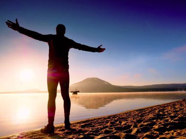 Kumsalda egzersiz adam. Egzersiz ve gölde germe etkin adam silüeti