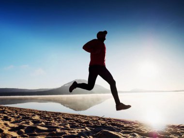 Kumsalda egzersiz adam. Egzersiz ve gölde germe etkin adam silüeti