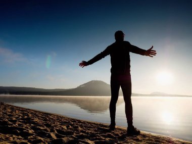 Kumsalda egzersiz adam. Egzersiz ve gölde germe etkin adam silüeti