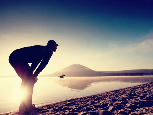 Homme faisant de l'exercice sur la plage. Silhouette de l'homme actif faisant de l'exercice et s'étirant au lac — Photo