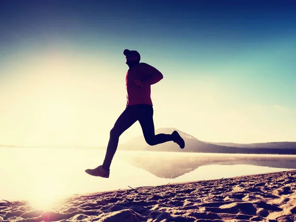 Kumsalda egzersiz adam. Egzersiz ve gölde germe etkin adam silüeti
