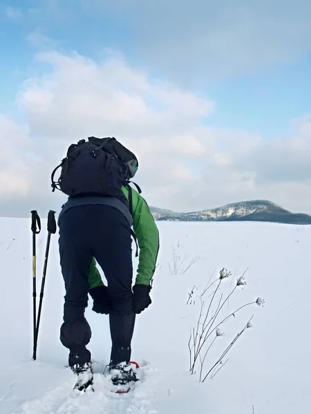 Turista che controlla le ciaspole. Escursionista con giacca invernale e grande zaino passeggiata sulla neve — Foto Stock