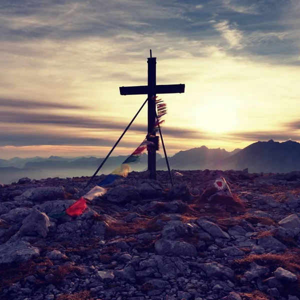 Big wooden cross at mountain peak in wind with Buddhist praying flags.  Cross on top of Alp peak — Stock Photo, Image