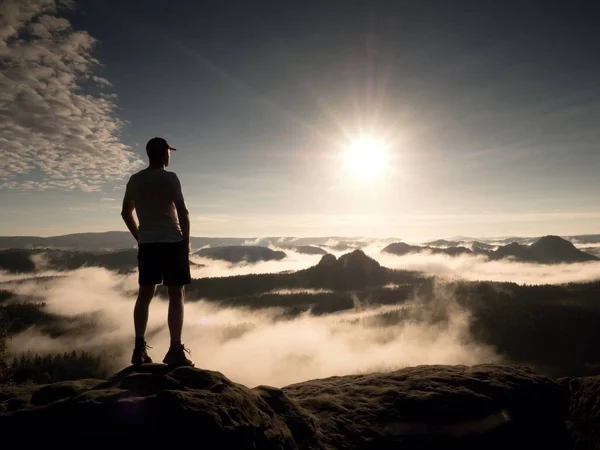 Mann auf dem Gipfel eines Berges mit Blick auf die neblige Landschaft. fühlen Sie sich frei — Stockfoto