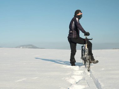Motorcu dağ bisikleti üzerinde kar drift bastırıyor. Güneşli kış hava dondur. Motorcu derin karda Bisiklet bastırıyor