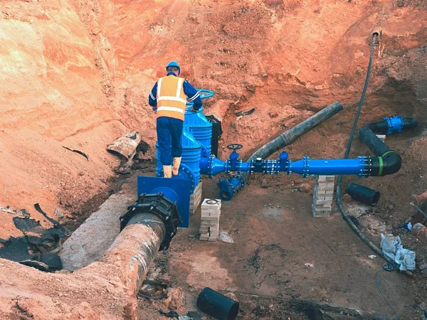 Trabajador en ropa de seguridad conducto de válvula de accionamiento en la ciudad de tubería de agua potable — Foto de Stock