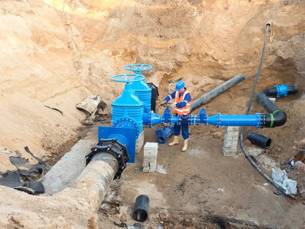 Travailleur dans les vêtements de sécurité conduit de soupape d'entraînement sur le tuyau d'eau potable de la ville — Photo