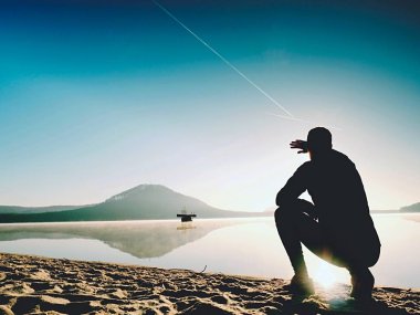 Kumsalda egzersiz adam. Egzersiz ve gölde germe etkin adam silüeti